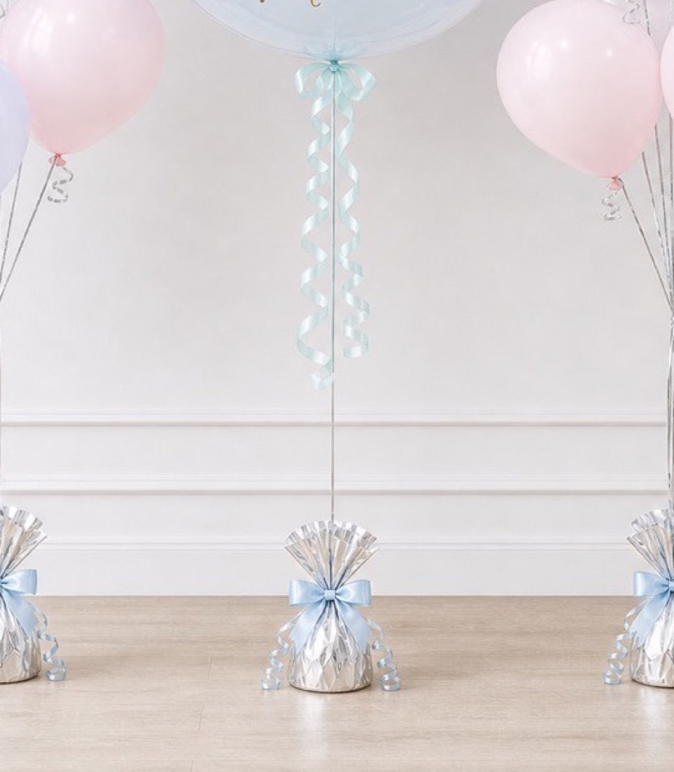 Elegant party decoration featuring pink balloons, light blue ribbon bows, silver metallic gift bags, and cascading aqua streamers on white ceiling.