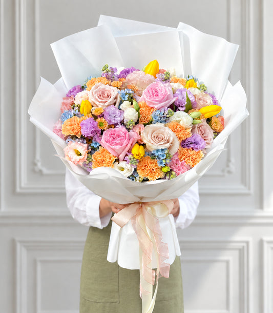 Full front studio view of pastel mixed rose tulip and carnation bouquet