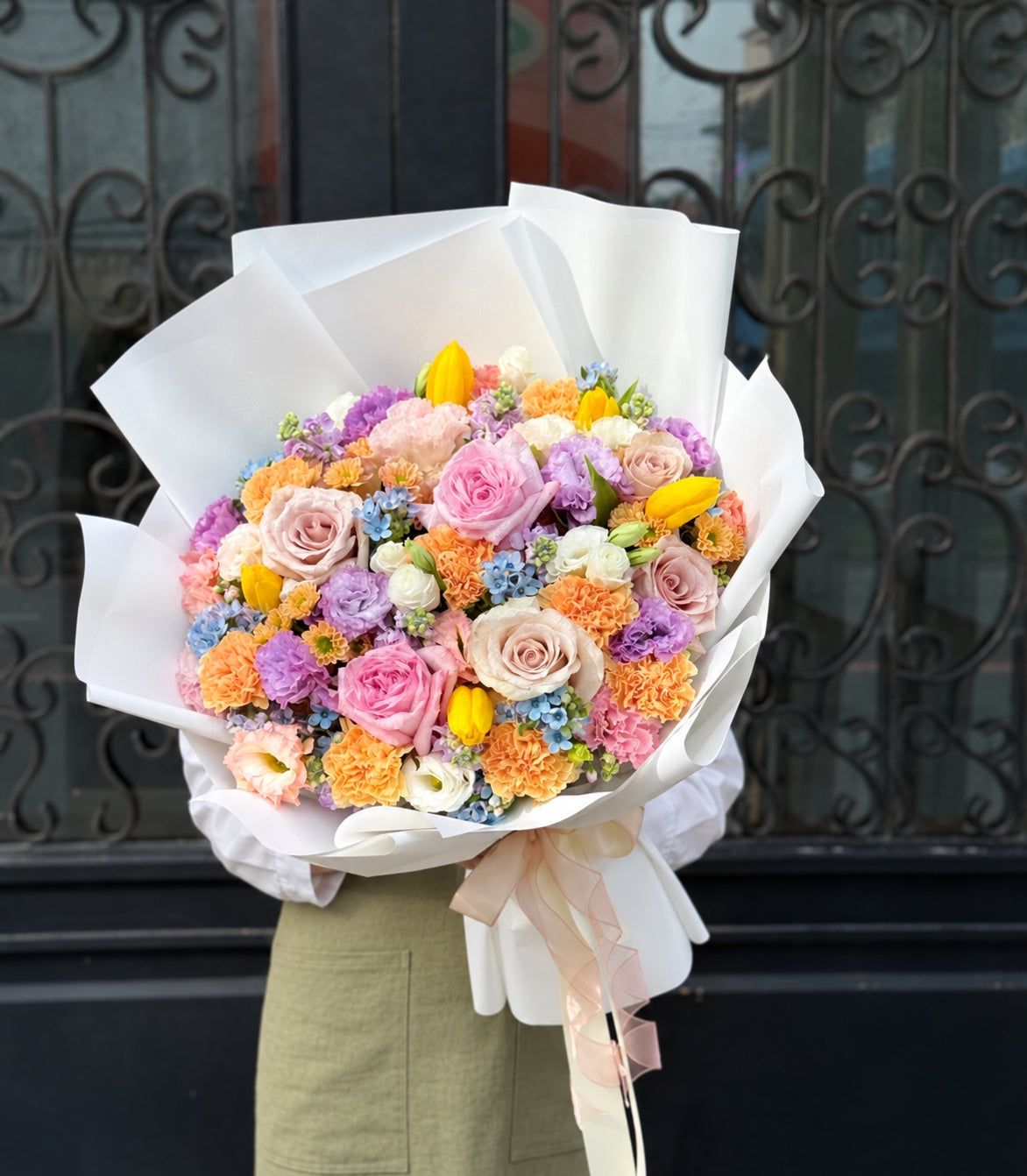 Model-held outdoor view of pastel mixed flower bouquet