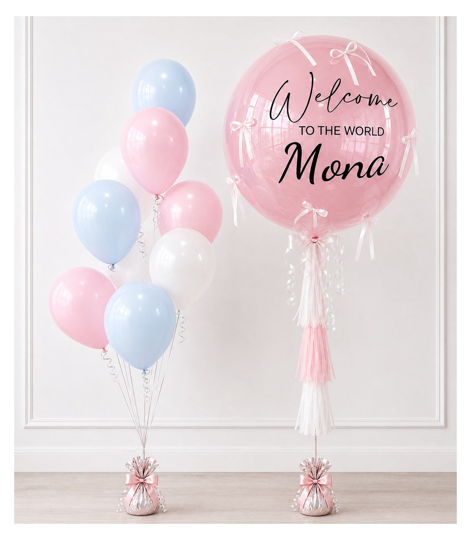 Pink and blue balloon arrangement with large personalized "Welcome to the World Mona" sphere balloon and tassel decorations.