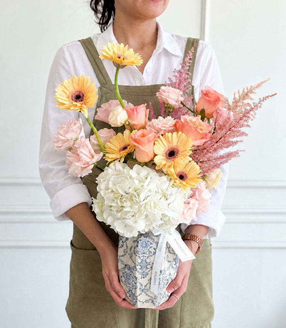 Elegant vase arrangement with vibrant yellow Gerbera daisies, peach roses,
