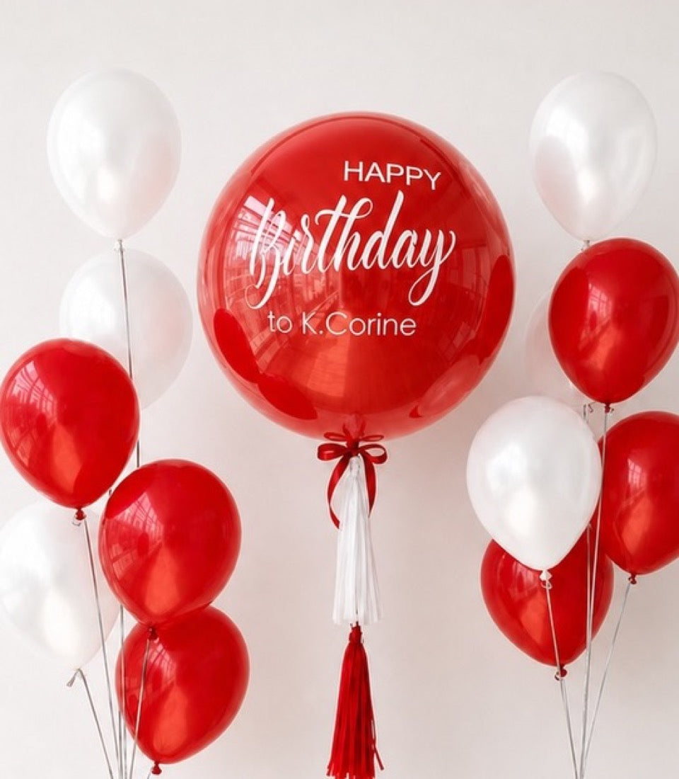 Red and white balloon bouquet with large personalized red bubble balloon reading "Happy Birthday to K.Corine" and red tassels.