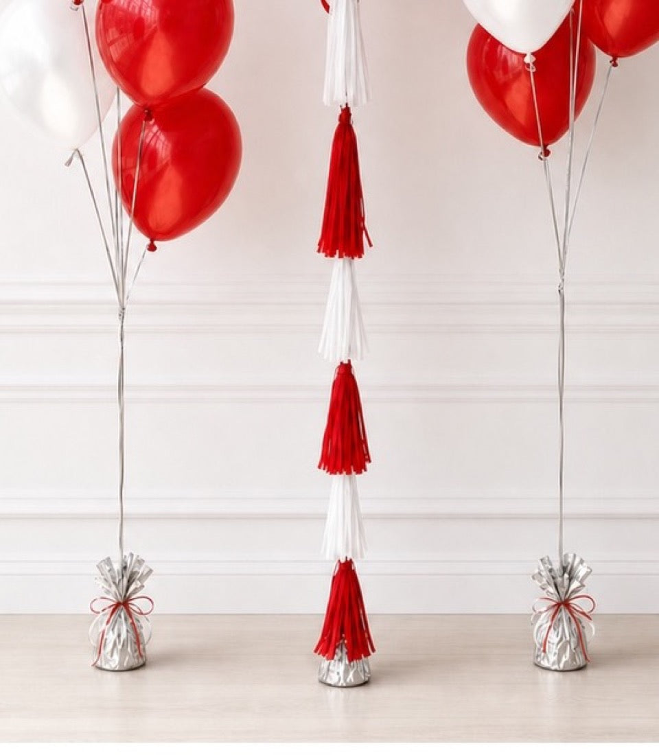 Red and white balloon bouquet set with tassel garlands and silver weighted bases for party decoration.