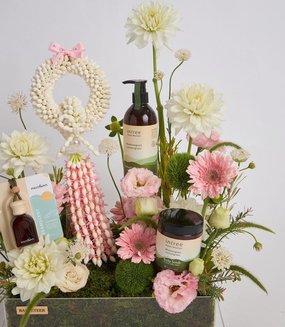 Luxe spa gift set with cream and pink flowers, beaded pearl wreath, Intree lemongrass body products, and botanical arrangements on moss base.