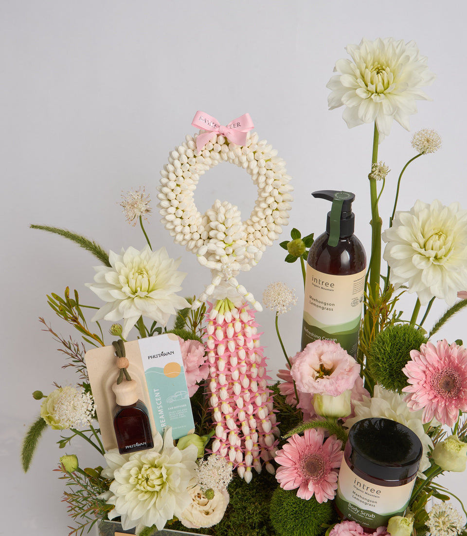 Luxury skincare gift set with white pearl wreath, pink bow, intree products, pink and white flowers, and moss arrangement on neutral background.
