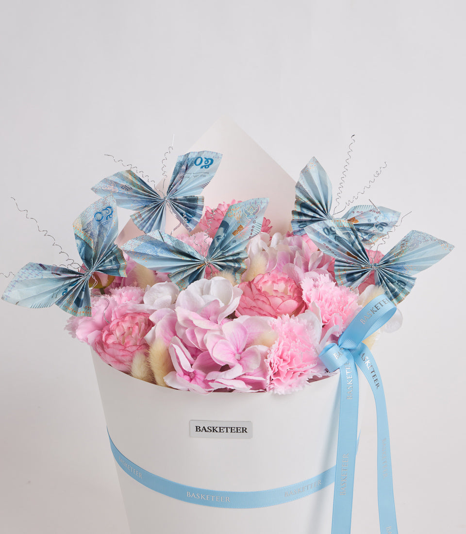# Alt Text

Luxury white hat box with pink peonies, blue decorative butterflies made from currency notes, and light blue ribbon bow branded "BASKETEER".