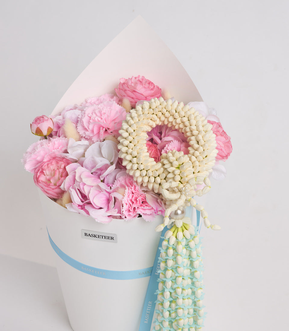 Luxurious floral gift box featuring pink peonies, white jasmine beads, and cream orchids with blue ribbon, by Basketeer.