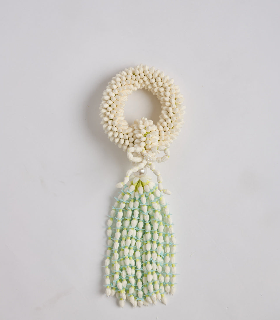 White jasmine flower garland lei with beaded circular top and cascading tassel, displayed against neutral background.