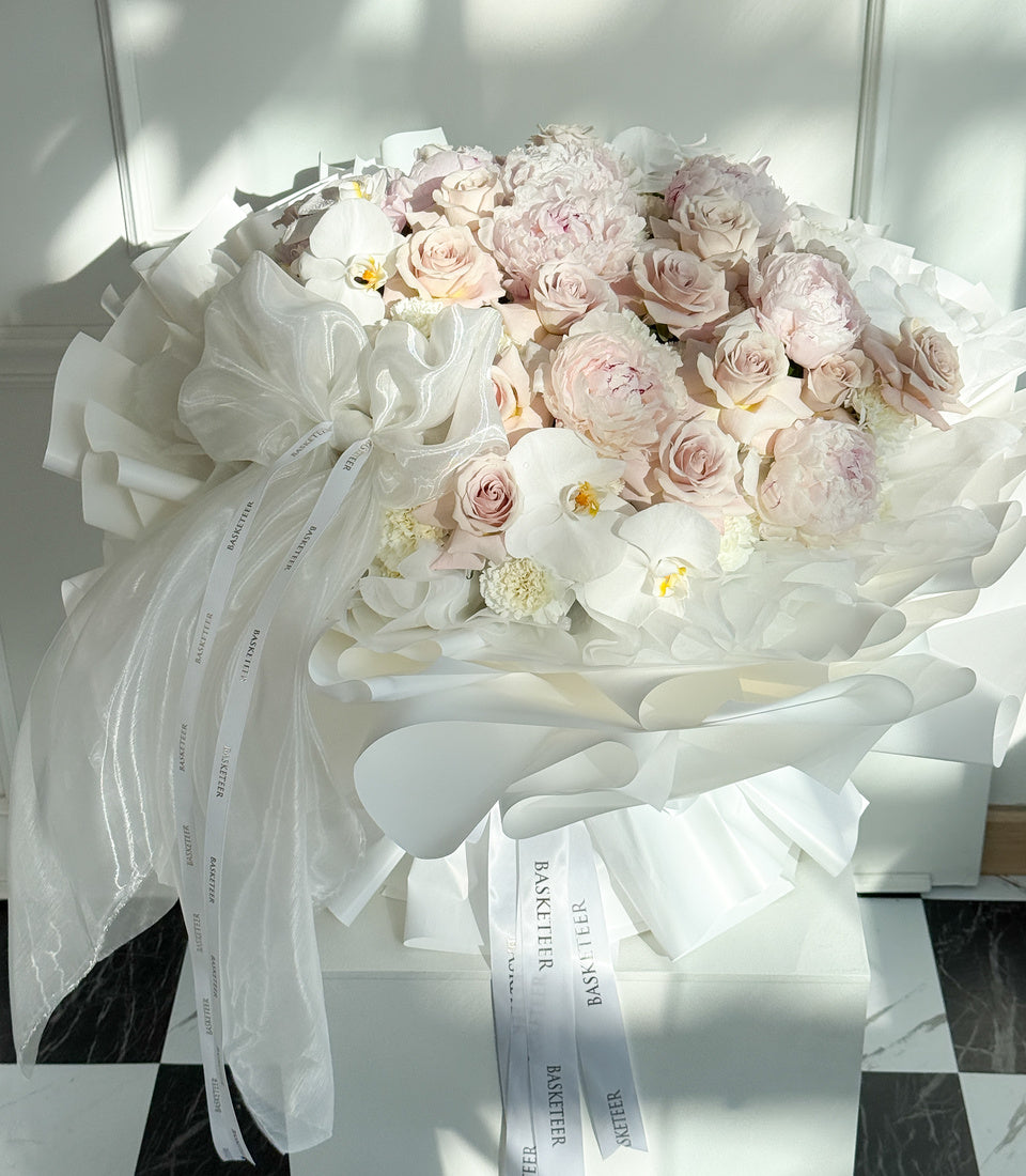 Angled close-up of pink peonies, blush roses and white orchids