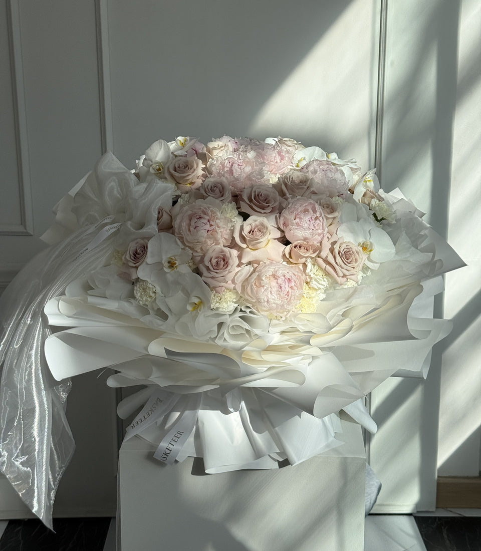 Full view of oversized pink peony rose and white orchid bouquet