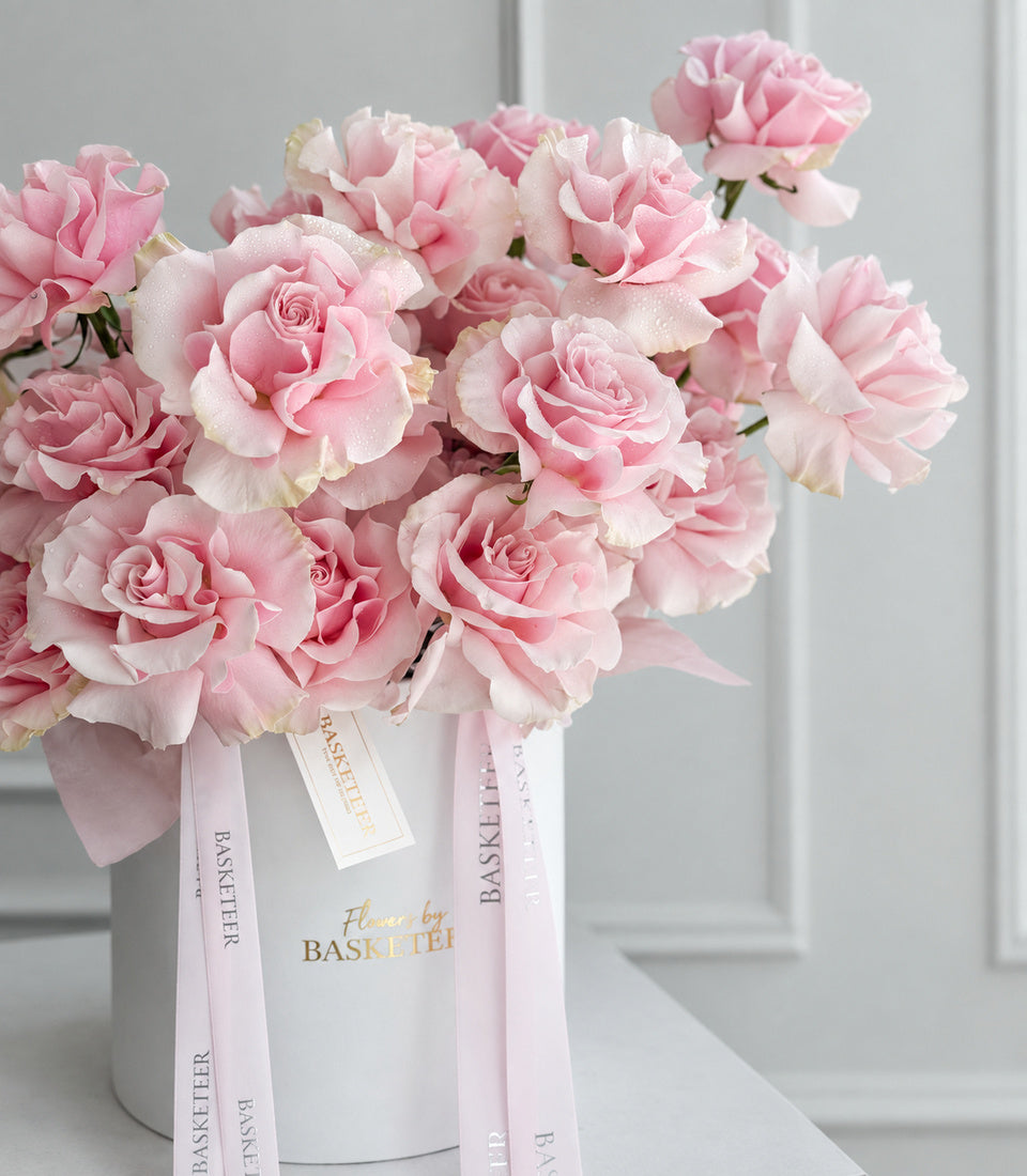 Angled close-up of pink Mondial roses in white leather flower box