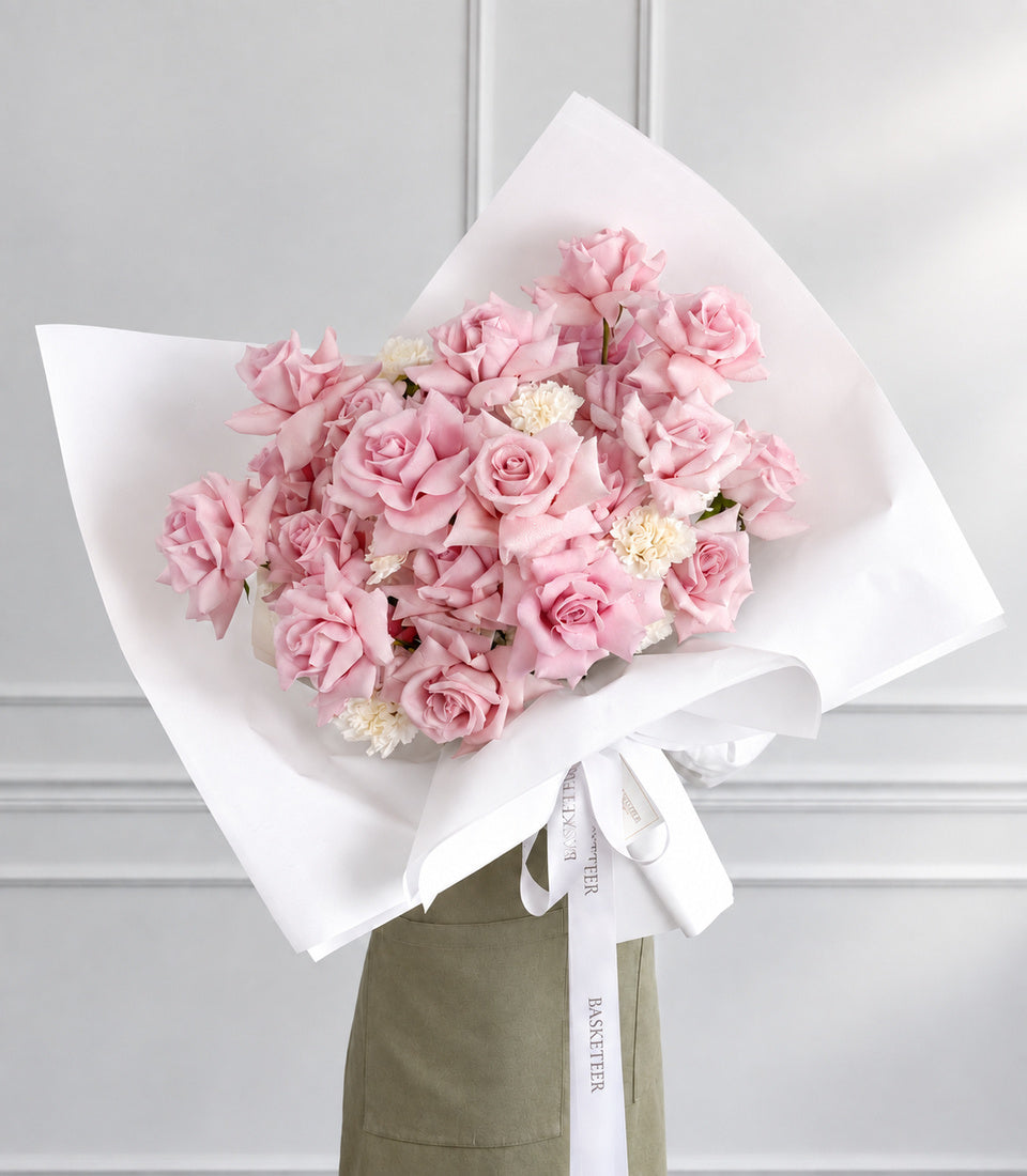 Angled model-held view of pink rose and white carnation bouquet