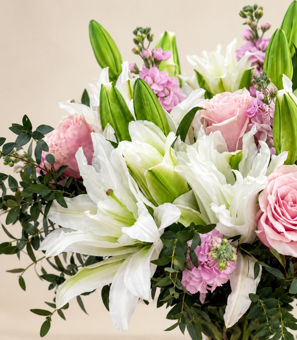 Close-up of white lilies, pink roses, and soft pink flowers in the Roselily Blush arrangement