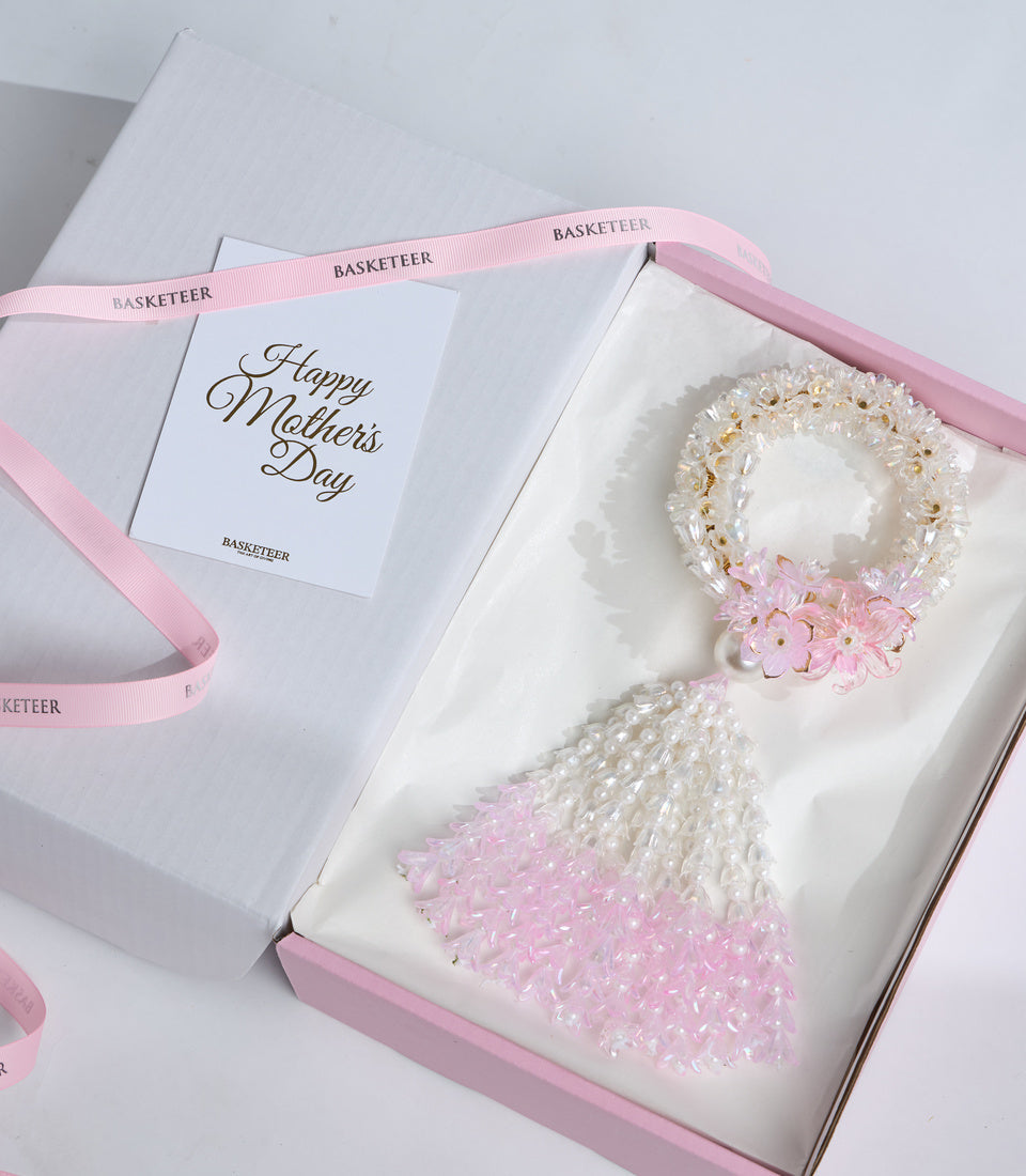 Elegant Mother's Day gift set by Basketeer featuring two beaded bracelets with pink and white pearl beads and delicate pink flowers, presented in pink-trimmed white packaging.