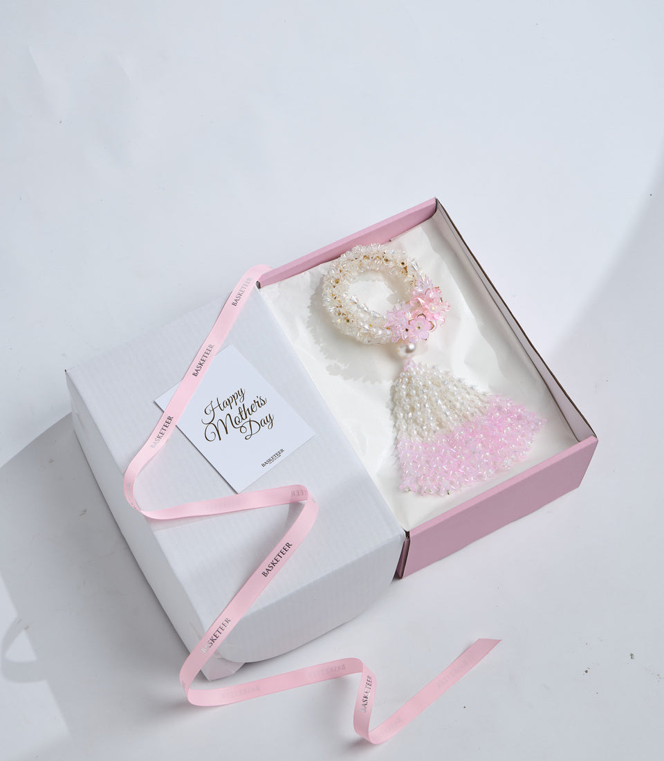 Elegant Mother's Day gift set with pearl beaded bracelet, pink flower accent, and white beaded tassel in pink-lined box with greeting card.