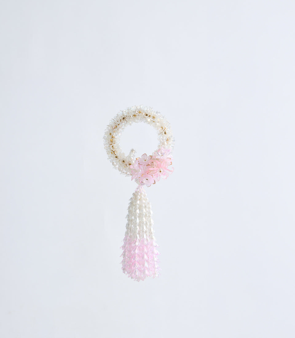 White and pink beaded tassel charm with circular loop top and cascading flower petal details against a light background.