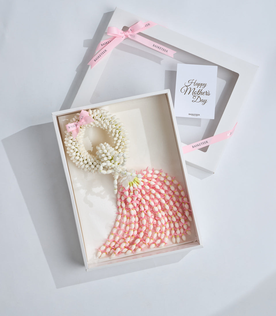 Elegant Mother's Day gift set with white pearl beaded bracelet, pink beaded sphere, pink ribbon bow, and greeting card in luxury packaging.
