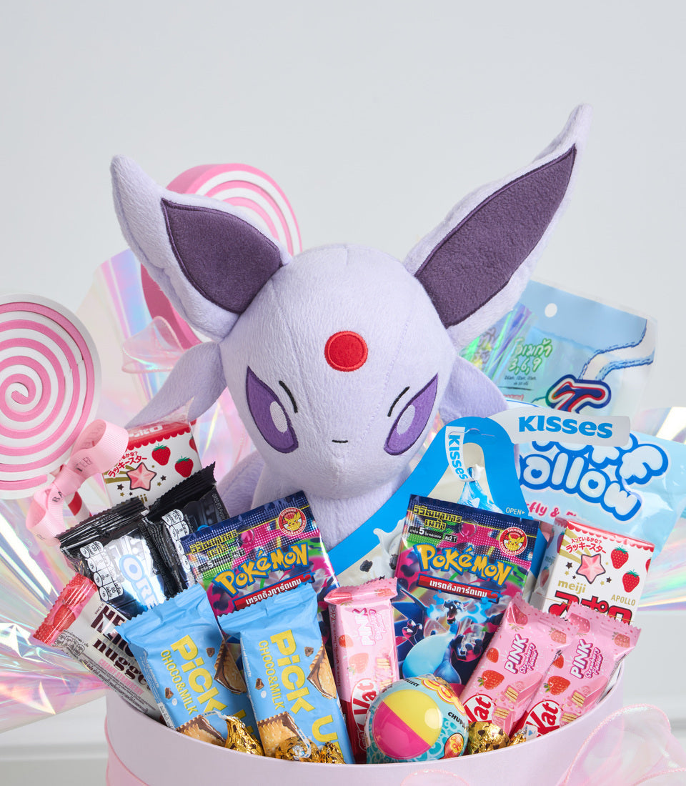 Purple plush Pokémon character surrounded by candies, cookies, and snacks in pink and blue packaging, arranged in white basket.