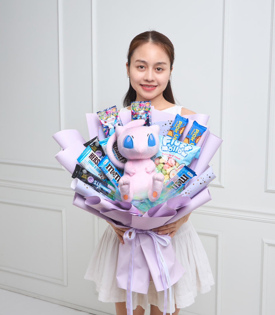 Young woman holding a lavender gift bouquet with a pink plush toy, candy, and snacks arranged with purple wrapping paper.