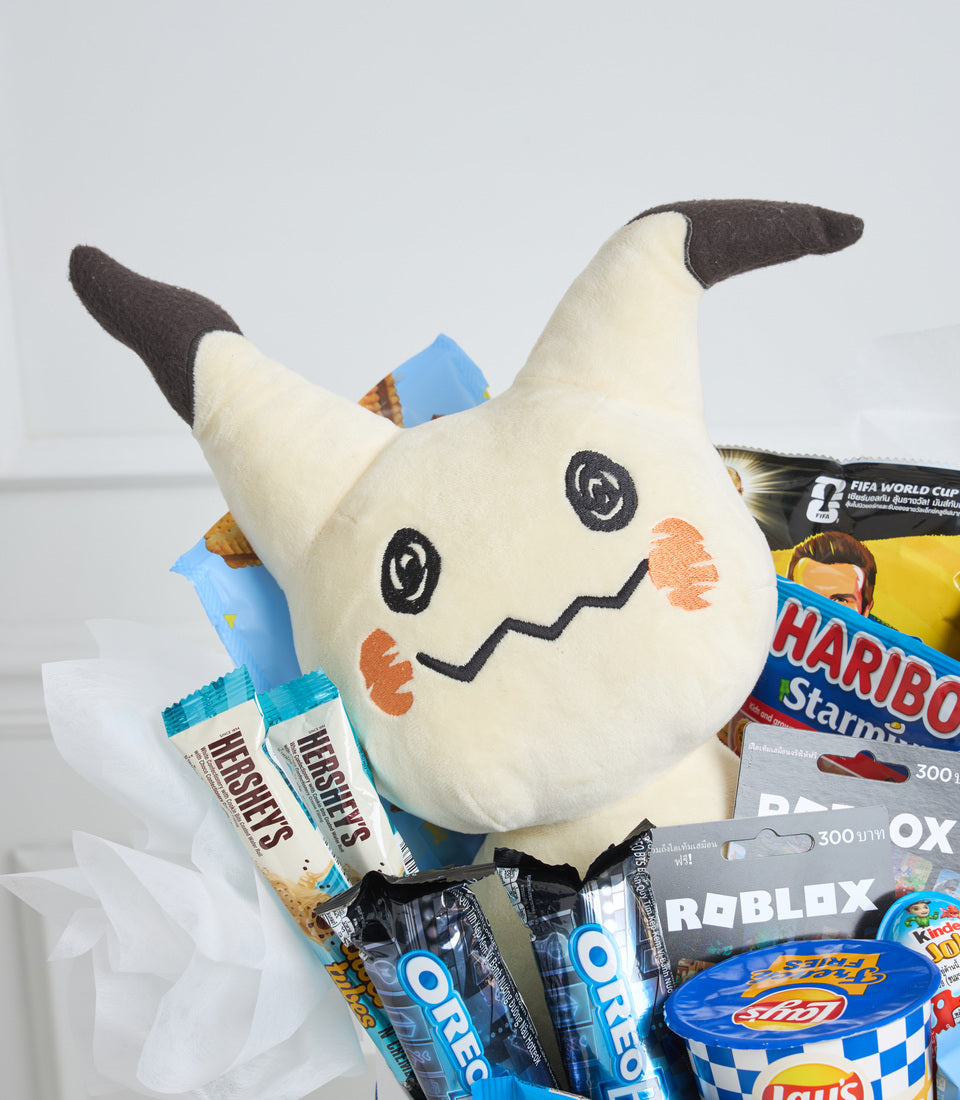 White plush Pikachu mascot with black horns, embroidered face details, surrounded by snacks and candy including Haribo, Roblox, and FIFA World Cup products.
