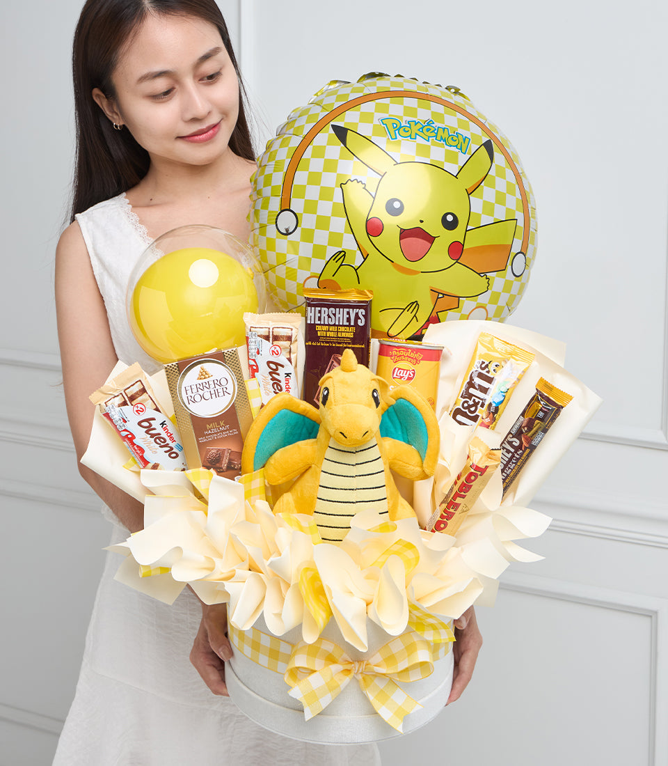 Pokemon Dragonite plush gift bouquet with yellow balloon, snacks, chocolate, and Pikachu foil balloon on white background.