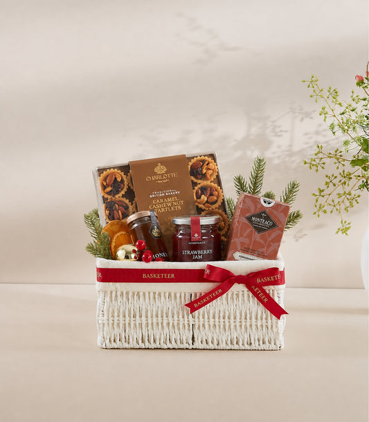 Basketeer luxury gift hamper with a white woven wicker basket, tied