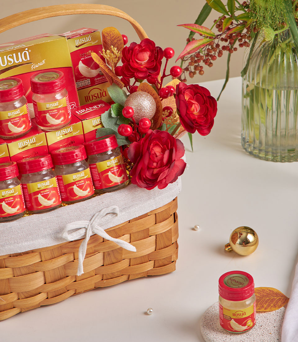 Woven wood gift basket with bird's nest drink bottles, red flowers, and gold accents for New Year gifting