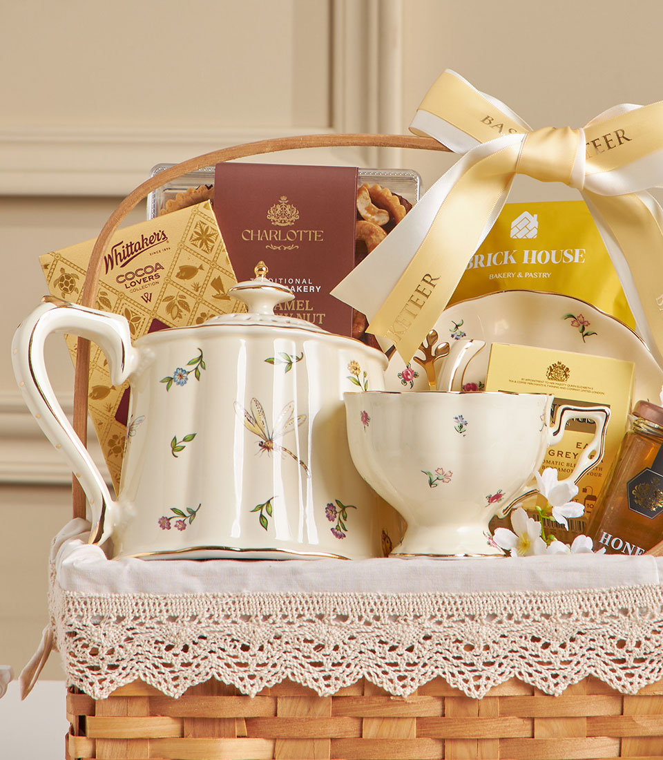 Cream ceramic tea set with floral motif in woven basket, paired with Earl Grey tea, chocolates, honey, and cashews for New