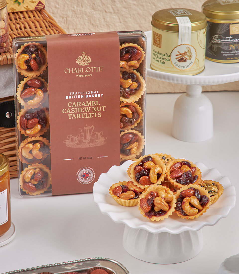 Gourmet New Year gift basket with Charlotte Bakery nut tartlets, specialty teas, and artisan confections on tiered cake