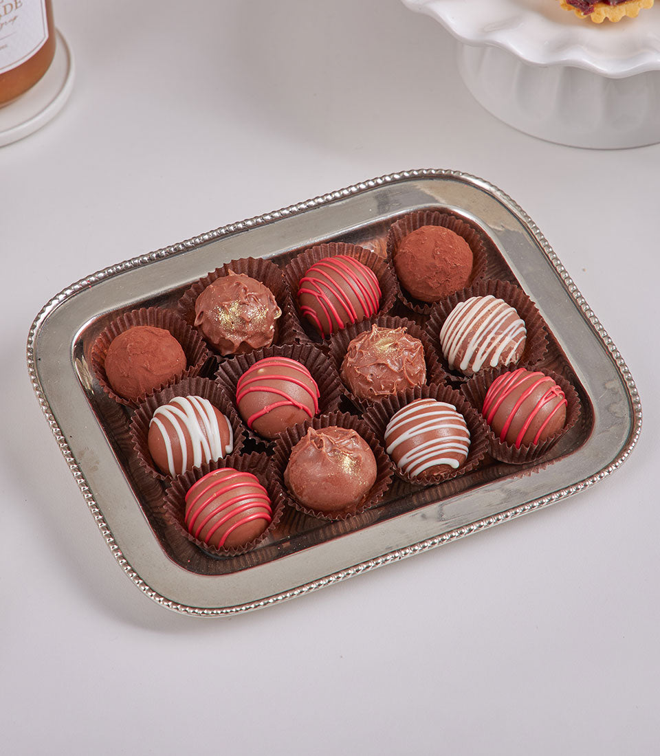 Luxury chocolate truffles gift set with dark and milk chocolate varieties, red and gold accents, silver tray for New Year