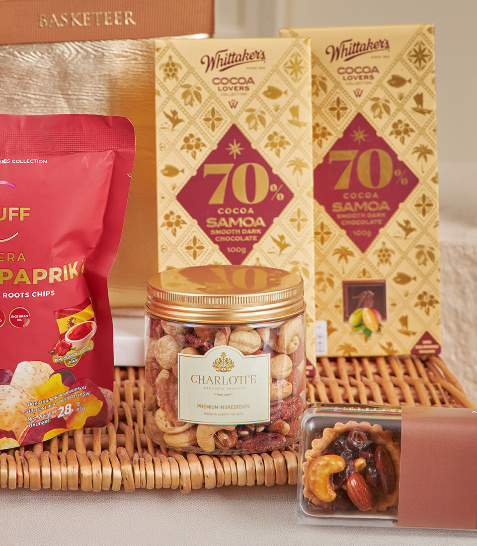 Wicker gift basket with dark chocolate bars, premium mixed nuts, artisan tart, and gourmet snacks for New Year celebrations