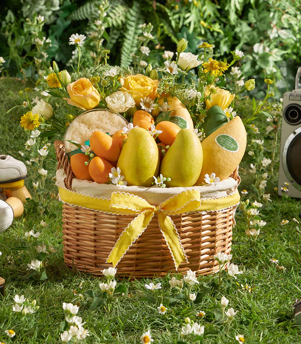 Luxury wicker basket with yellow mangoes, fresh fruit, sticky rice, and yellow-white roses for gifting