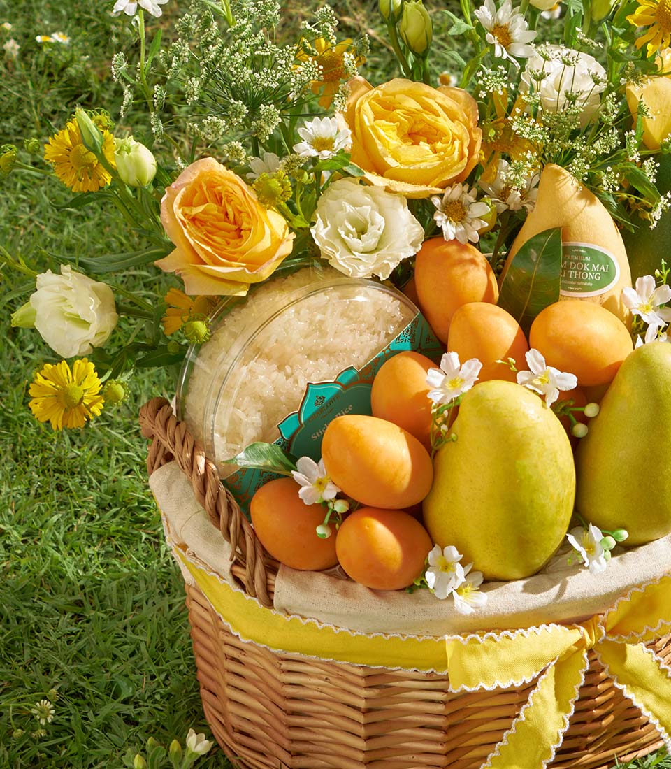 Luxury mango and mayongchid gift basket with fresh yellow and orange roses, daisies, sticky rice, and tropical fruit