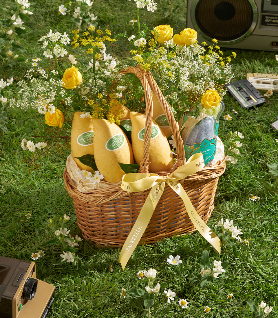 Nam Dok Mai mango gift basket with sticky rice, yellow roses, and wildflowers in wicker hamper
