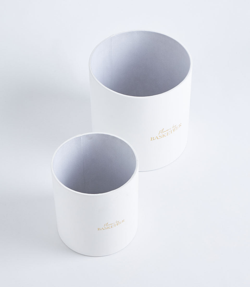 A pair of premium Basketeer round gift boxes in white with elegant gold branding