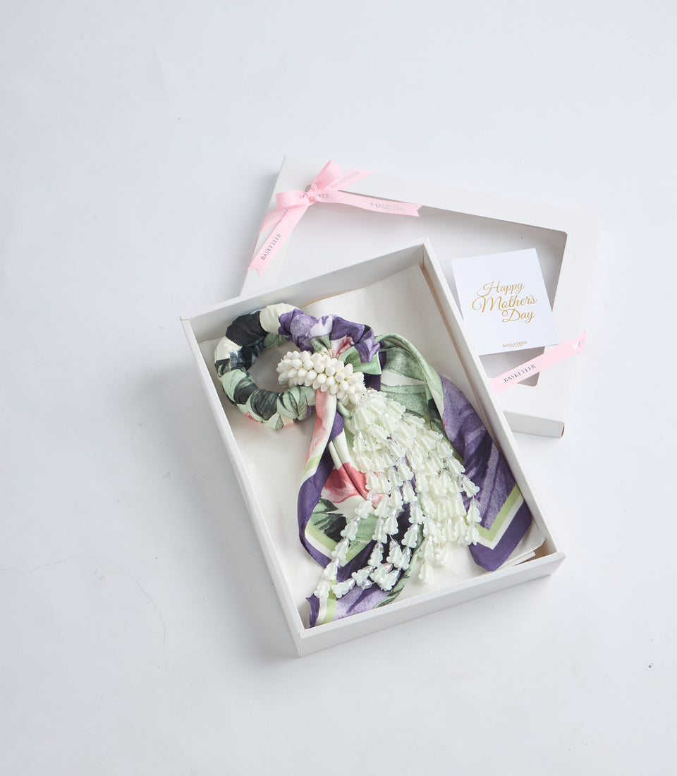 Elegant Mother's Day gift set featuring a floral fabric corsage with white, purple, and pink flowers, green leaves, and black accents, presented in a white box with pink ribbon and greeting card.