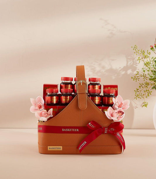 Premium leather gift basket with scotch bottles, red ribbon, and fresh pink orchids