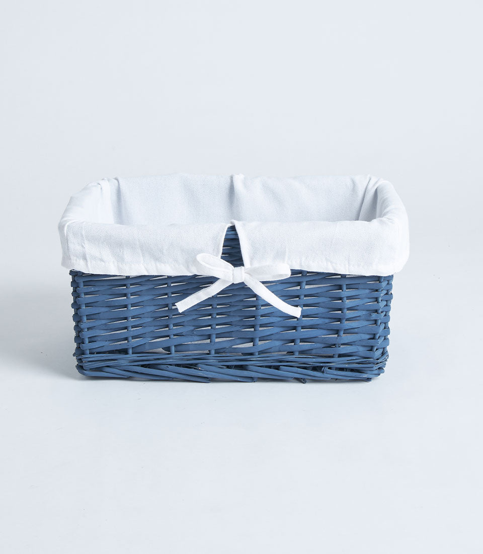 Navy wicker rectangular gift basket with white fabric lining and ribbon bow