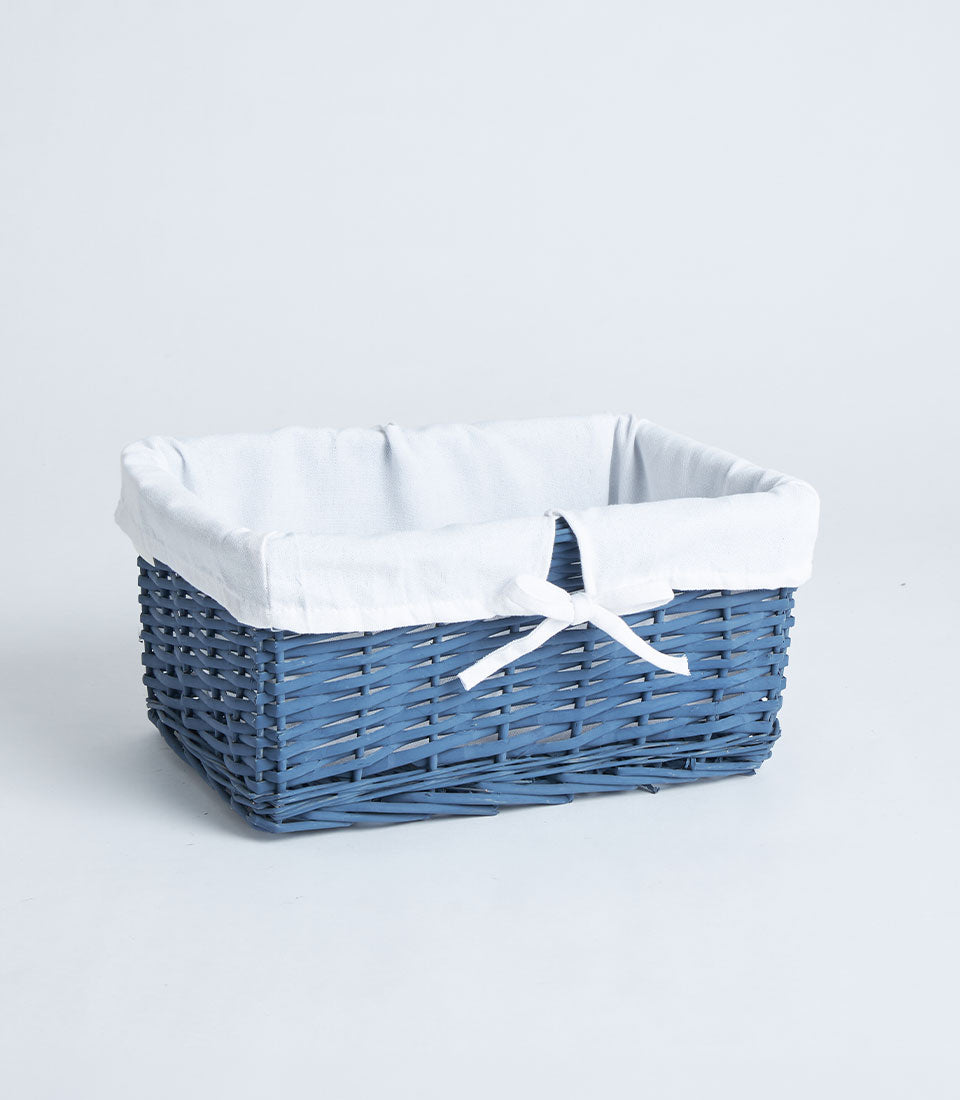 Navy wicker rectangular gift basket with white fabric lining and ribbon bow