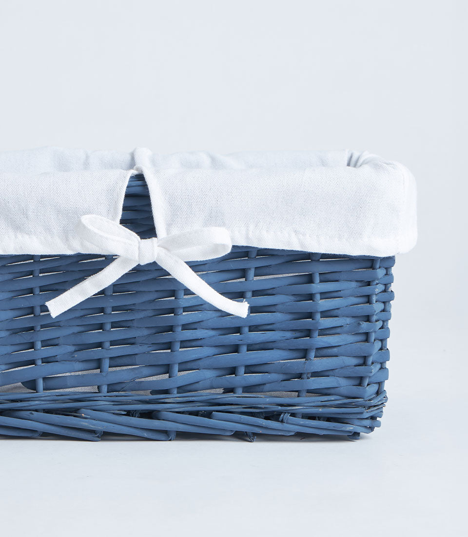 Navy wicker gift basket with white fabric lining and ribbon bow