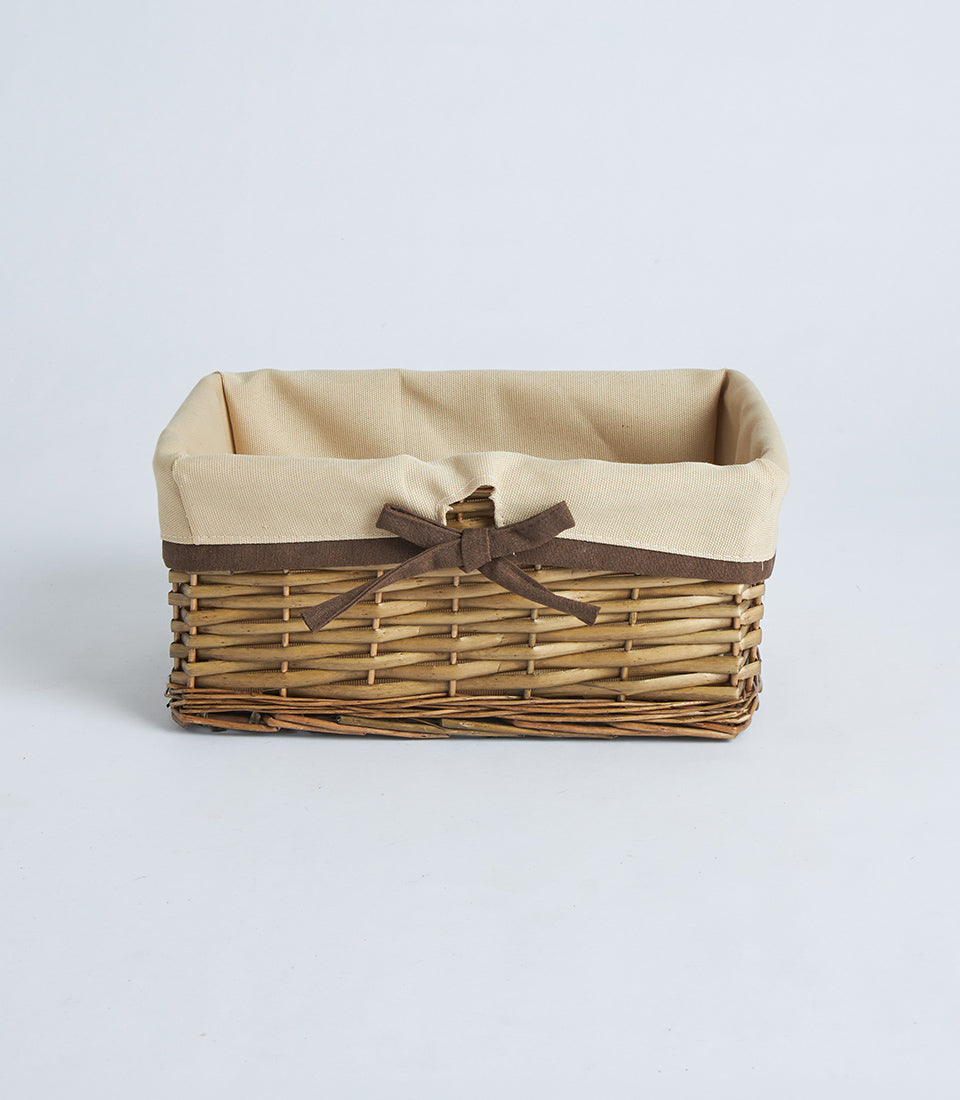 Natural woven wicker rectangular basket with beige fabric lining and brown ribbon bow