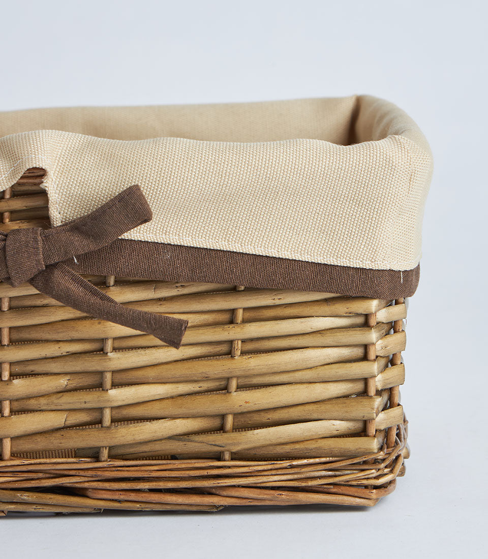 Natural wicker rectangular gift basket with cream fabric lining and brown ribbon bow