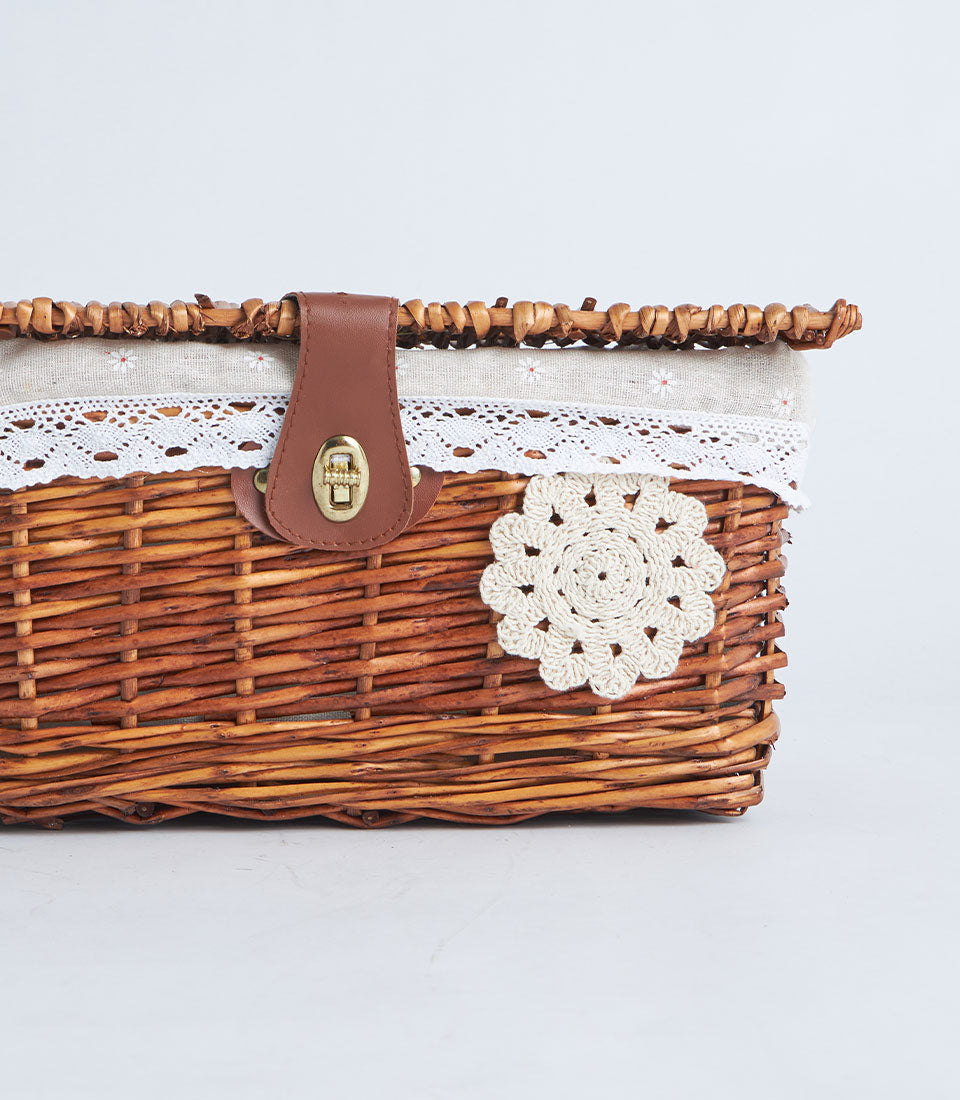 Handwoven rectangular wicker storage basket with cream fabric trim, lace accents, and leather strap closure