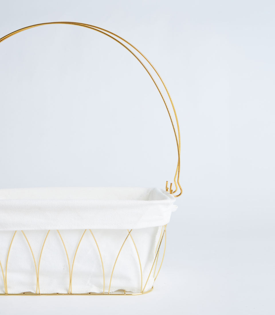 Gold wire frame basket with white fabric lining and arched handle for luxury gift presentation