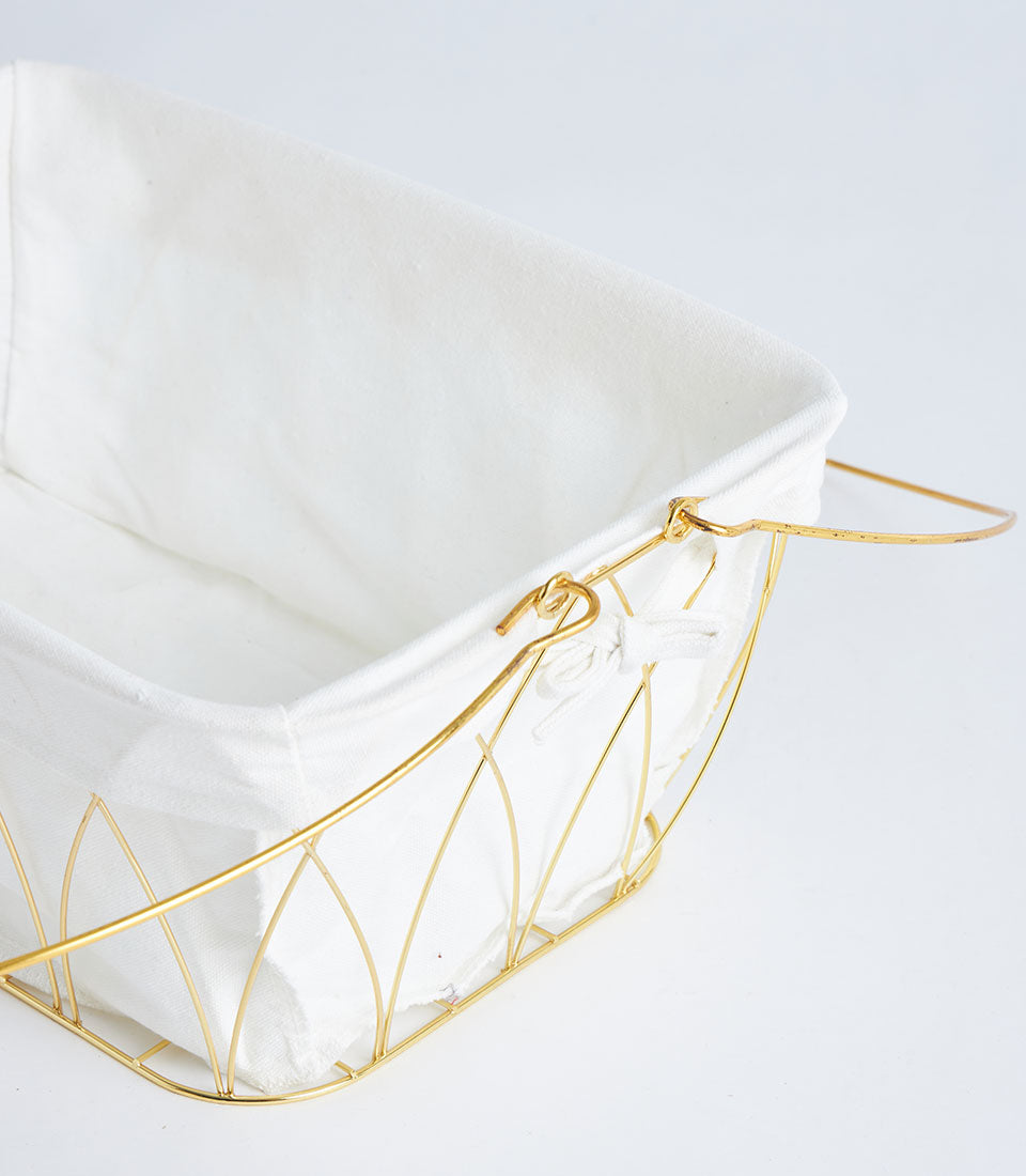 Gold metal wire storage basket with white fabric lining and decorative diamond pattern