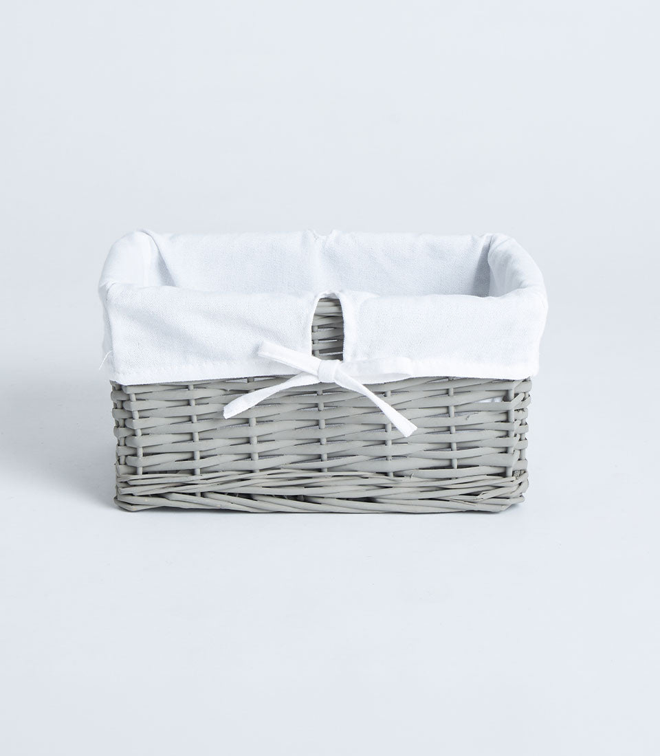 Light grey woven wicker basket with soft fabric lining and white ribbon bow
