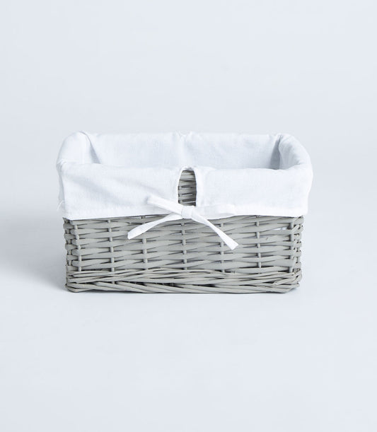 Light grey woven wicker basket with soft fabric lining and white ribbon bow