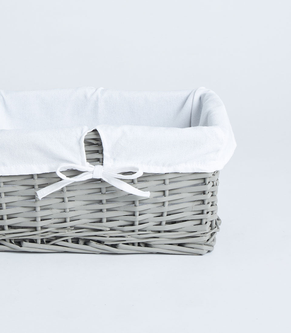 Handwoven rectangular wicker basket with light grey tone and white fabric lining