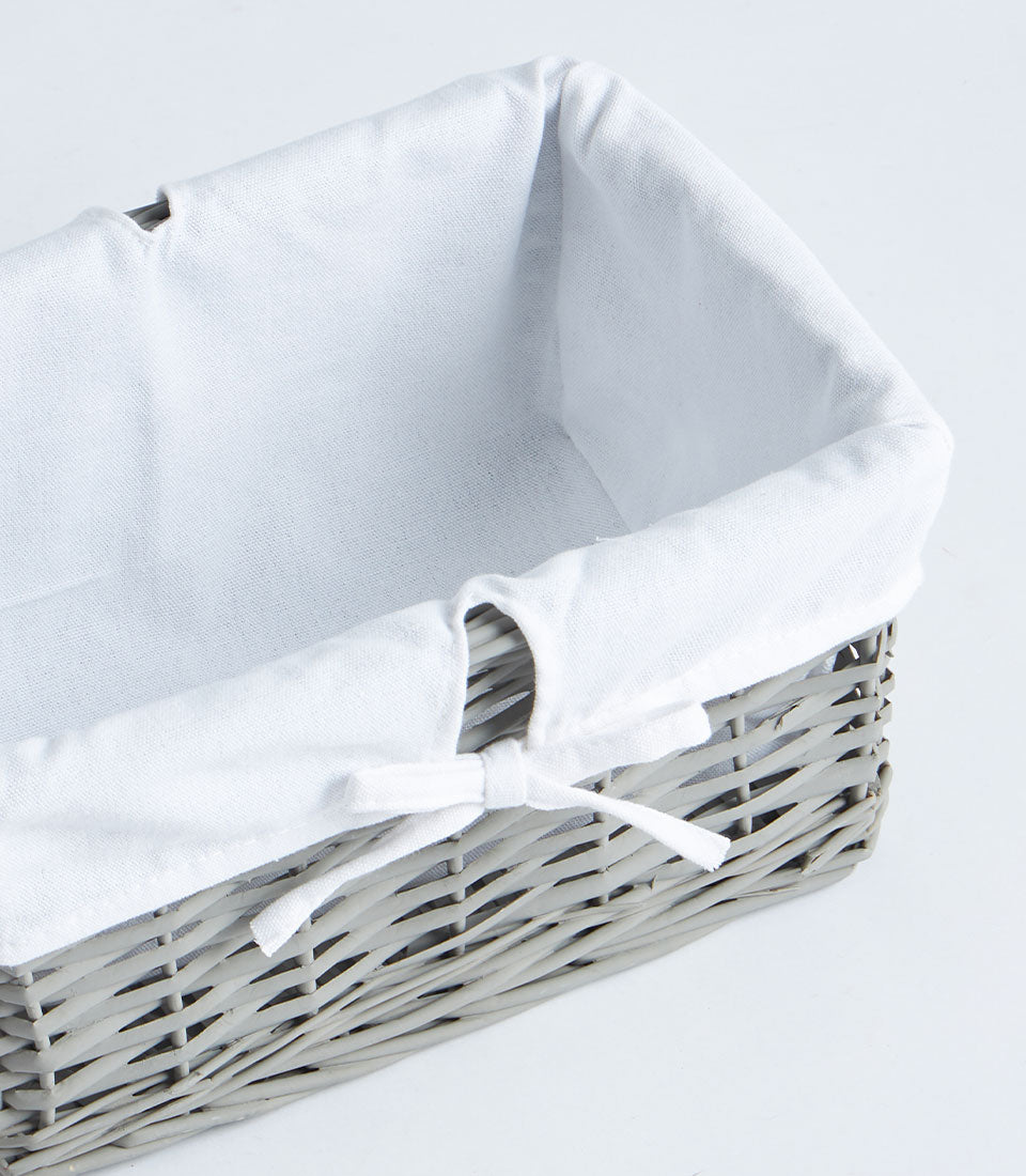 Light grey handwoven wicker basket with white fabric lining and bow detail for luxury gift hampers