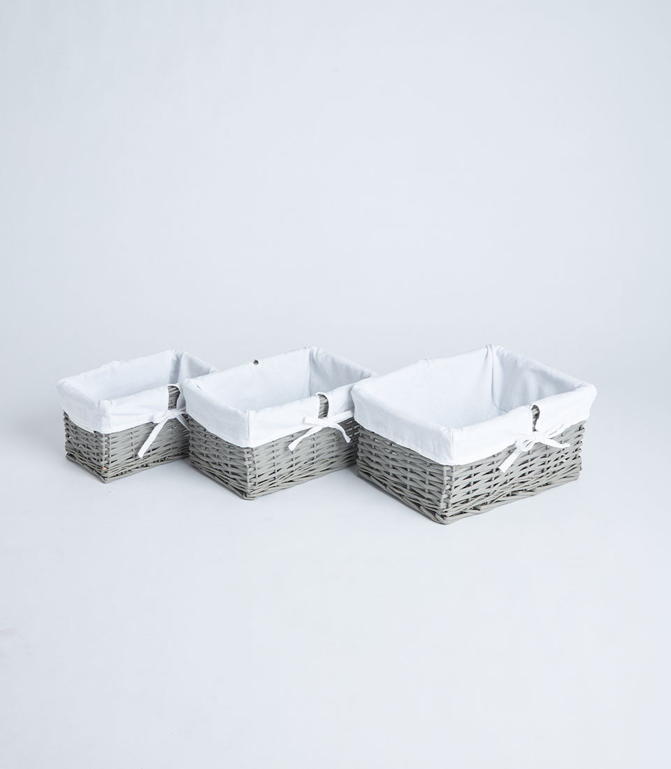 Handwoven rectangular wicker baskets with white fabric liners in grey tone, three sizes